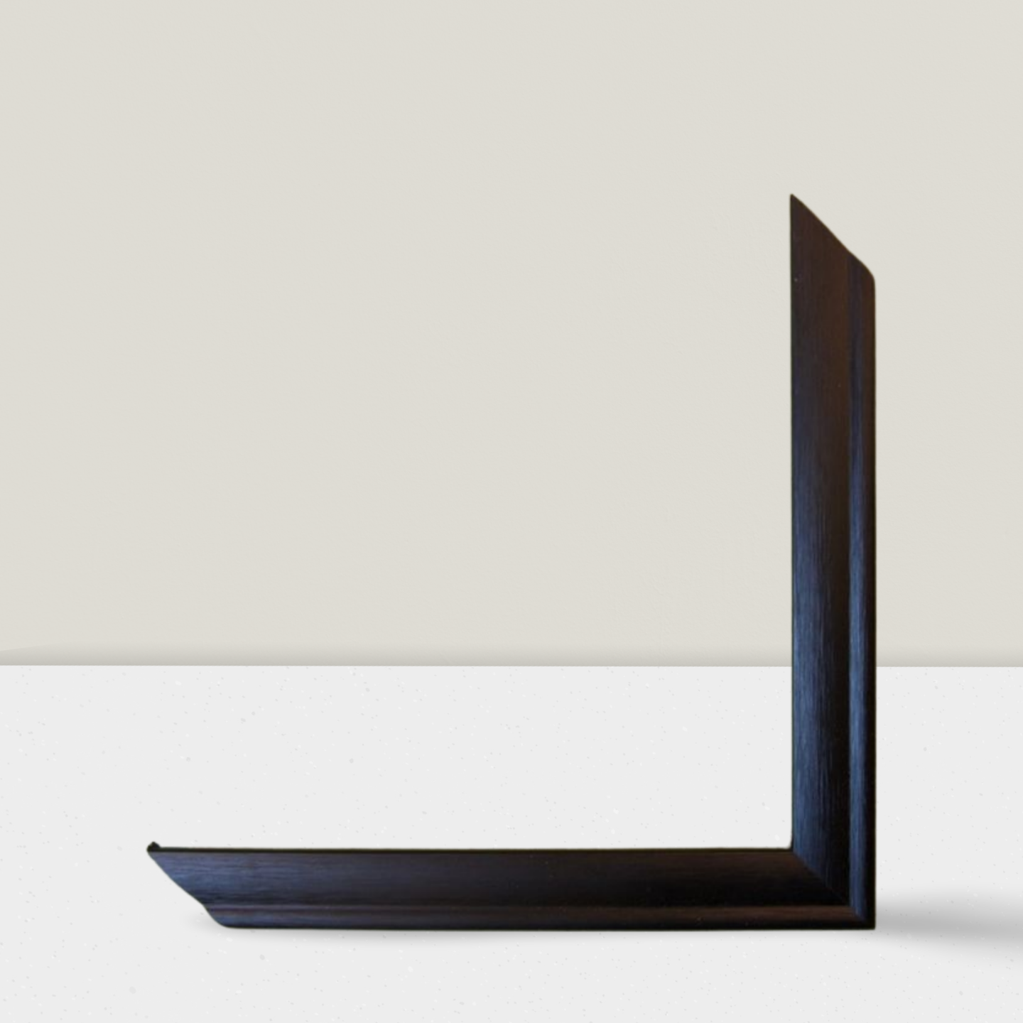 Black L-shaped bookend on a white surface with a light gray background